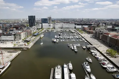 Ein Flusskreuzfahrtschiff von Thurgau Reisen im Hafen von Antwerpen während des Bunkerns. Das Schiff liegt an der Pier, während Besatzungsmitglieder mit dem Beladen von Treibstoff und Vorräten beschäftigt sind. Im Hintergrund sind die charakteristischen Gebäude des Hafens und die geschäftige Atmosphäre der Hafenaktivitäten sichtbar.