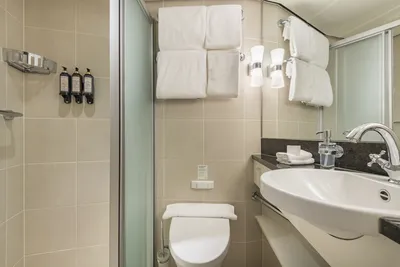 Das moderne Bad auf dem Flusskreuzfahrtschiff MS Edelweiss von Thurgau Reisen. Es zeigt ein elegantes Lavabo mit einem stilvollen Wasserhahn, Handtüchern und Pflegeprodukten, die sorgfältig angeordnet sind. Die hellen Fliesen und die geschmackvolle Beleuchtung schaffen eine angenehme und einladende Atmosphäre.