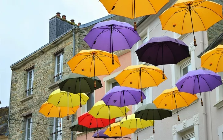 © Tanoz - stock.adobe.com - Regenschirme hängen in einer Straße in Cherbourg