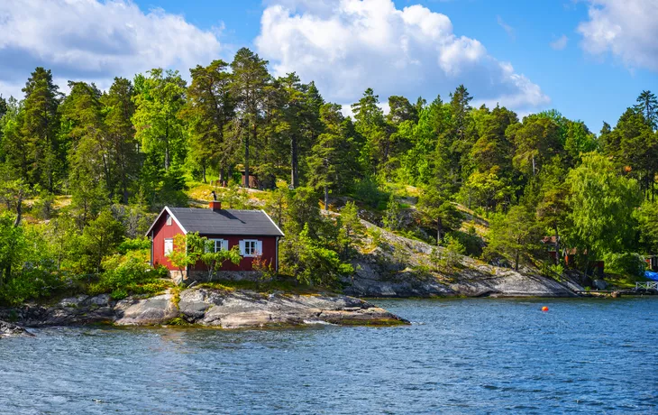 © pyty - stock.adobe.com - kleine rote Hütte an der skandinavischen Küste
