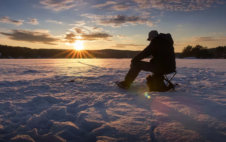 ©MarianneHydalsvik - stock.adobe.com - Eisfischen auf einem See in Norwegen bei Sonnenuntergang