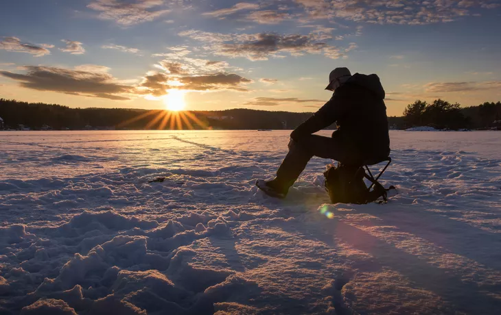 ©MarianneHydalsvik - stock.adobe.com - Eisfischen auf einem See in Norwegen bei Sonnenuntergang