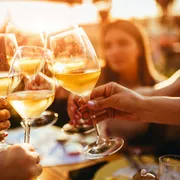 Menschen, die auf der Sommerterrasse eines Cafés mit Weingläsern anstoßen 