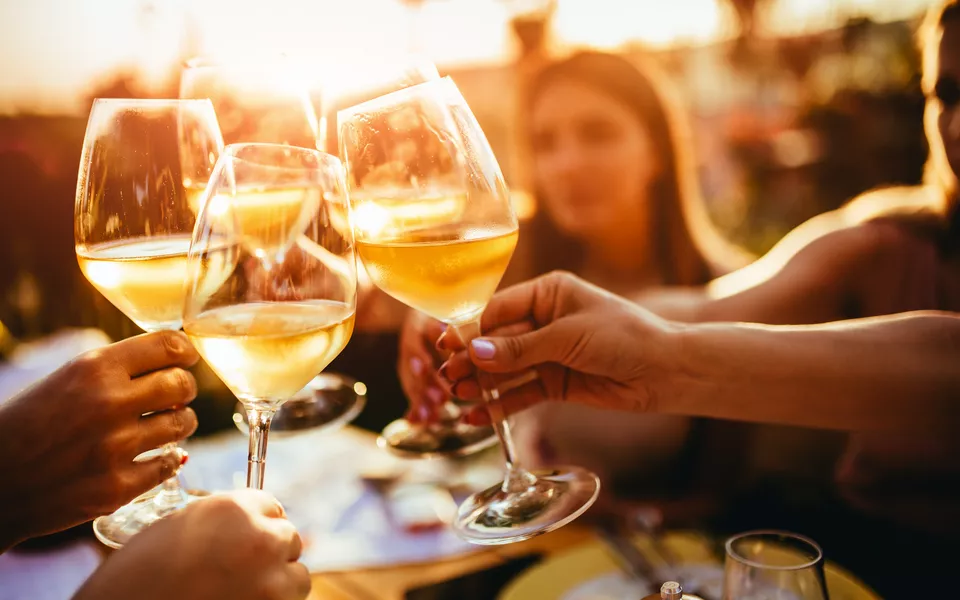 Menschen, die auf der Sommerterrasse eines Cafés mit Weingläsern anstoßen 
