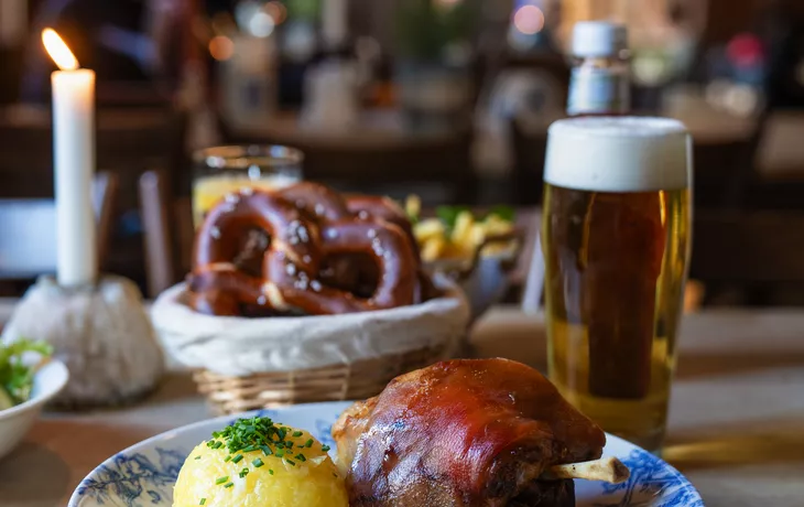 Traditionelle Schweinshaxe mit Knödel und Bier im gemütlichen Wirtshaus - © NIKIBA - stock.adobe.com