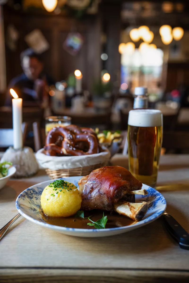 Traditionelle Schweinshaxe mit Knödel und Bier im gemütlichen Wirtshaus - © NIKIBA - stock.adobe.com